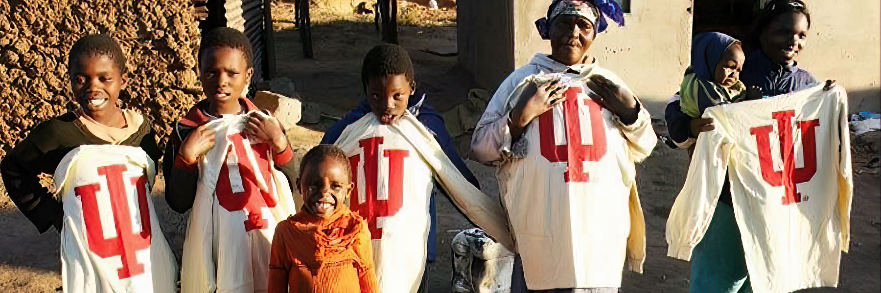 Community members at a study abroad program location holding IU shirts