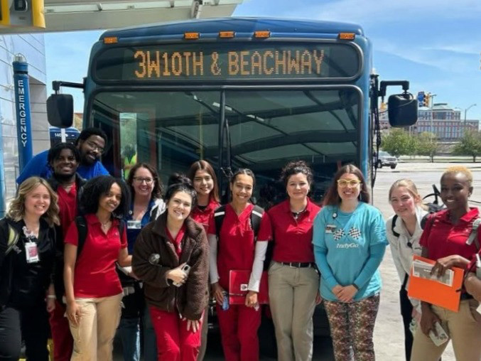 A group of nursing students stand in front of an IndyGo bus during a learning experience.