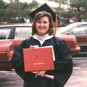 Marsha Hughes-Gay in a graduation cap and gown holding a red IU diploma cover