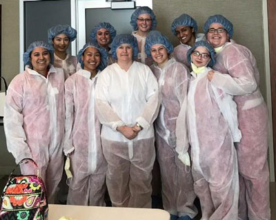 Dr. Marsha Hughes-Gay poses for a photo with a group of students in medical scrubs