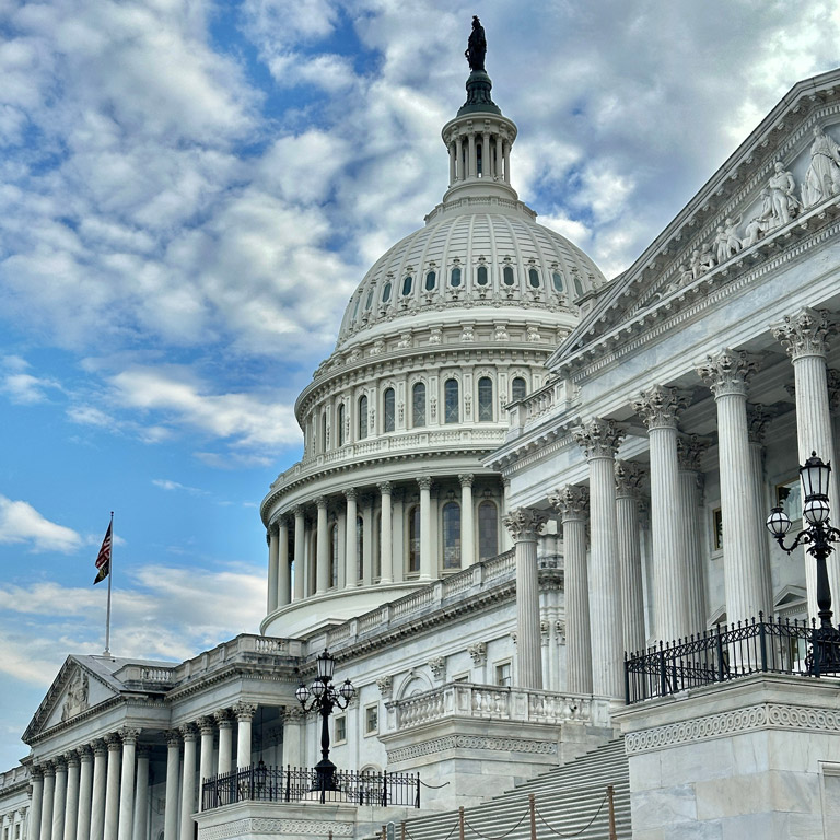 The U.S. Capitol building in Washington, D.C., with its dome and columns under a partly cloudy sky.