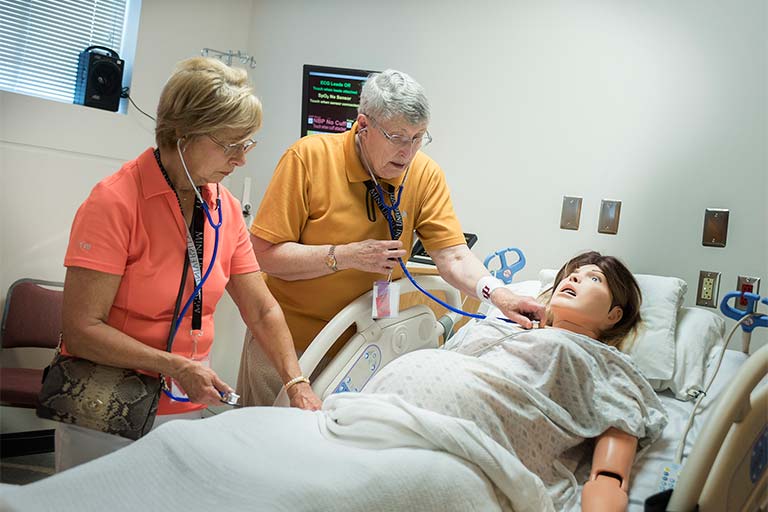 Two women examine manikin